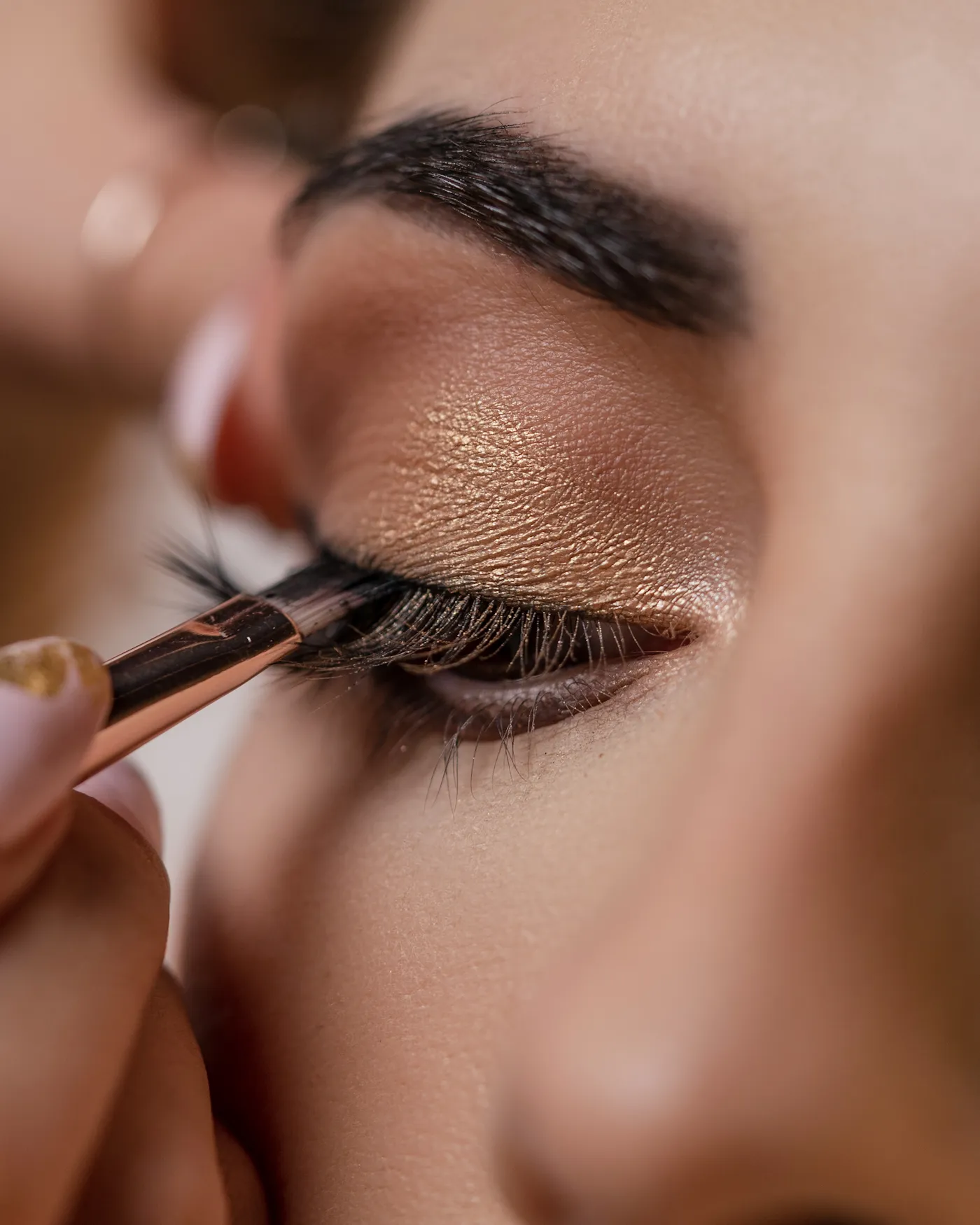 Close-up of a brush blending shimmer eyeshadow over flawless, even-toned skin