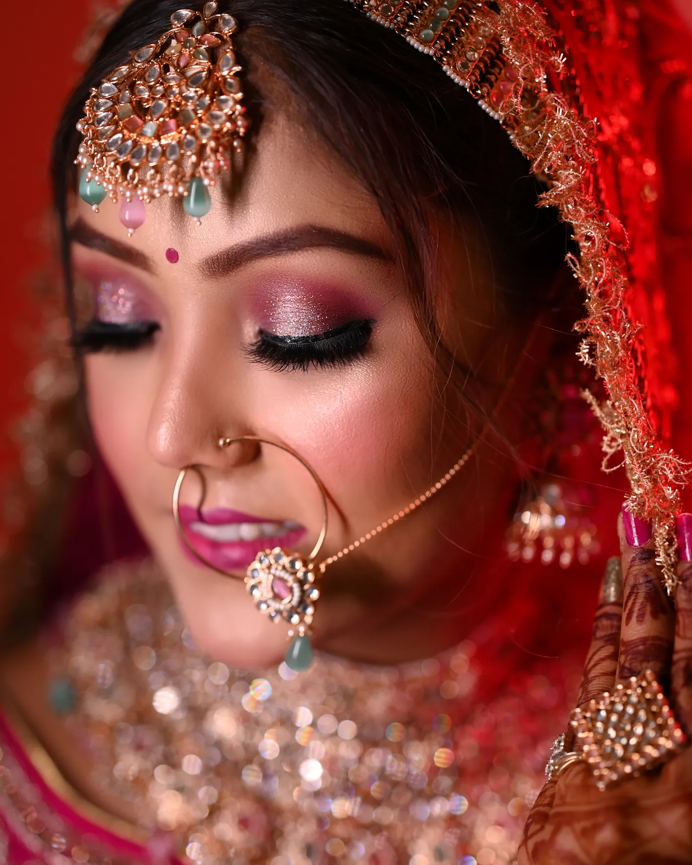 Bridal makeup detail with shimmering pink eyeshadow, nath and kundan jewellery on an Indian bride