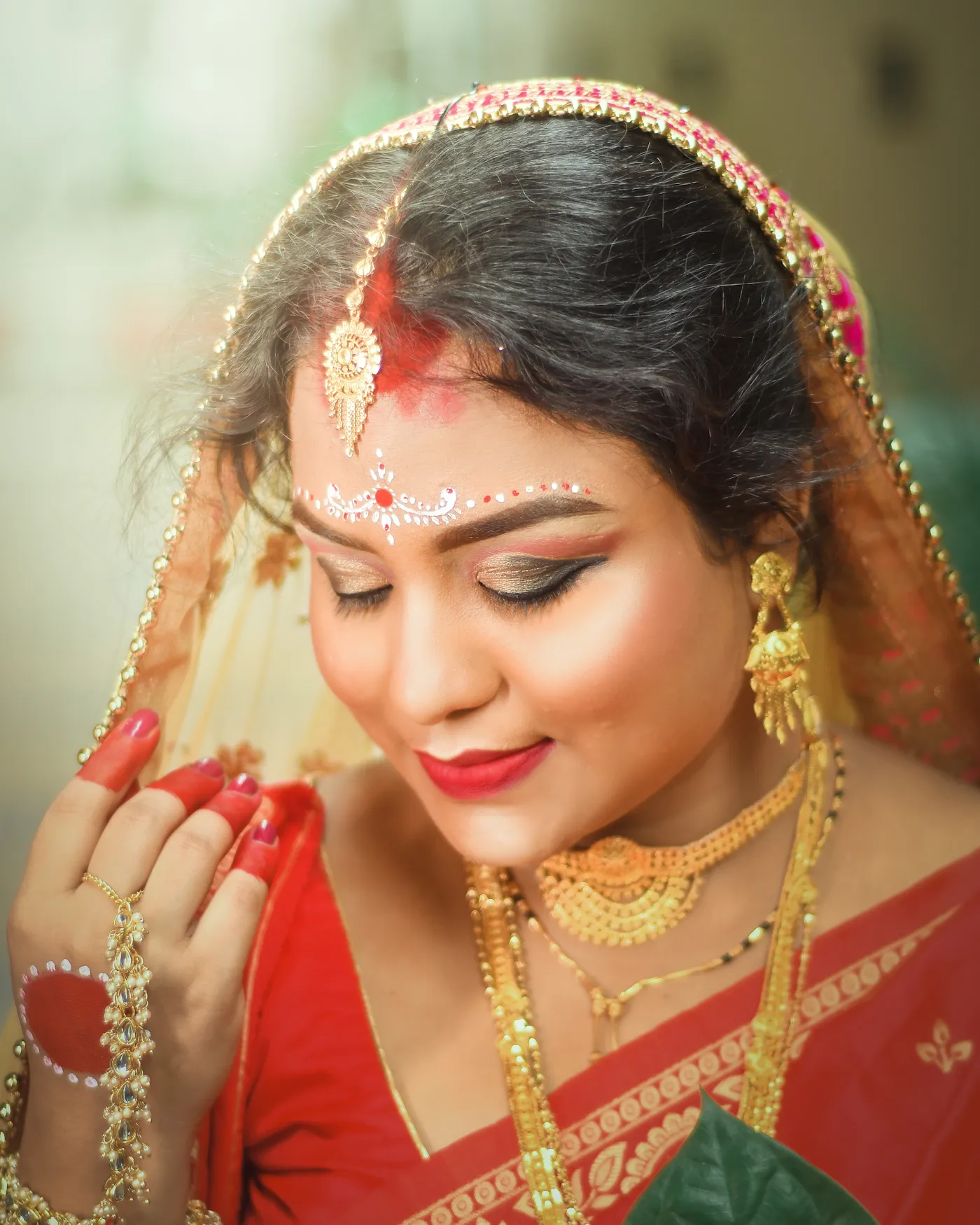 Smiling Indian woman in a red saree with sindoor, gold jewellery and festive makeup