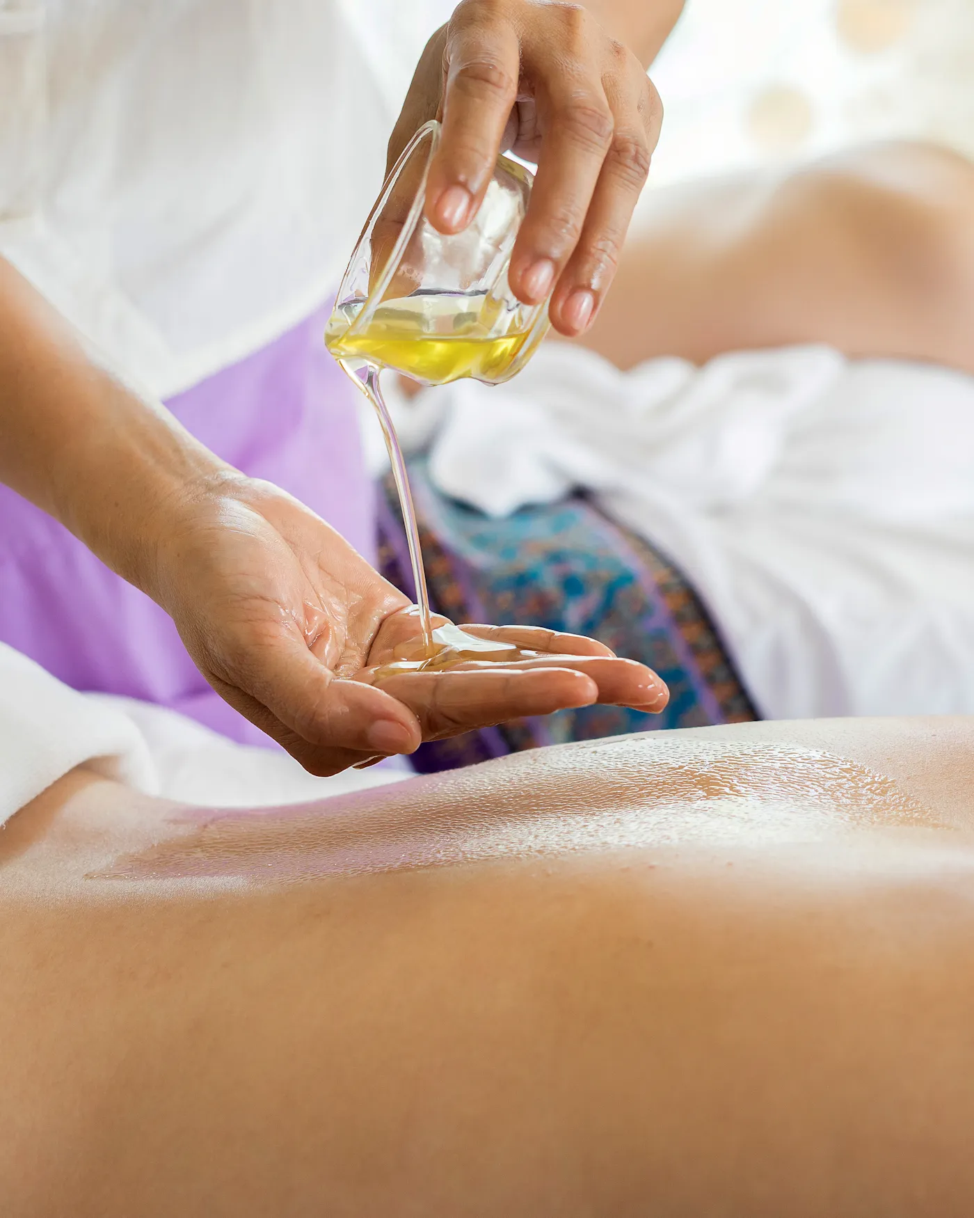 Therapist pouring warm massage oil during a relaxing pre-bridal spa treatment